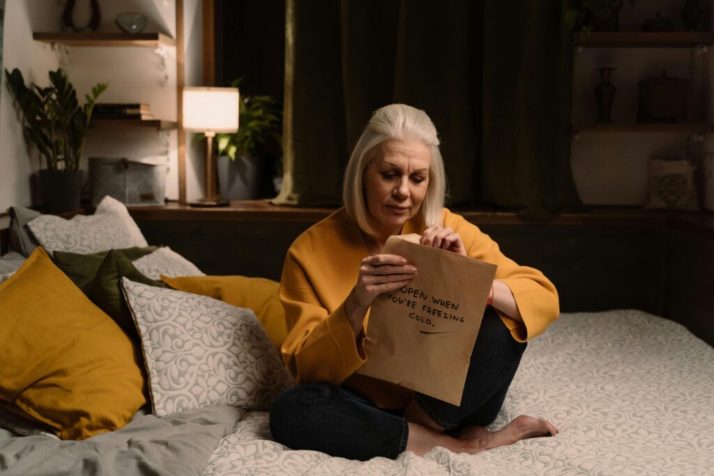 An old woman opening opening a package on her bed