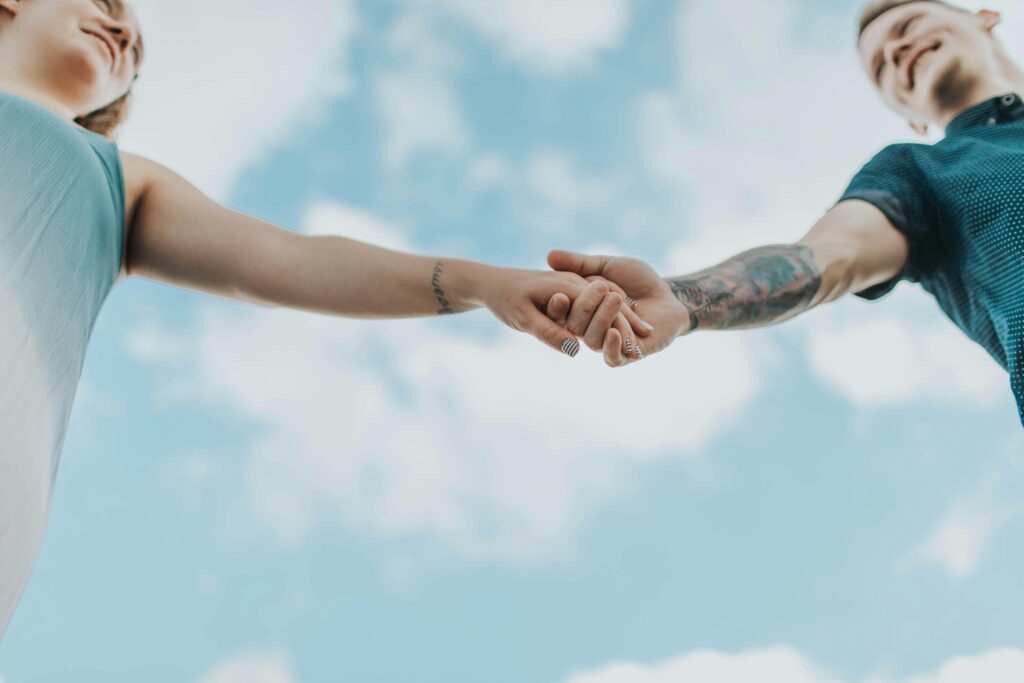 Two people holding hands under a big blue sky